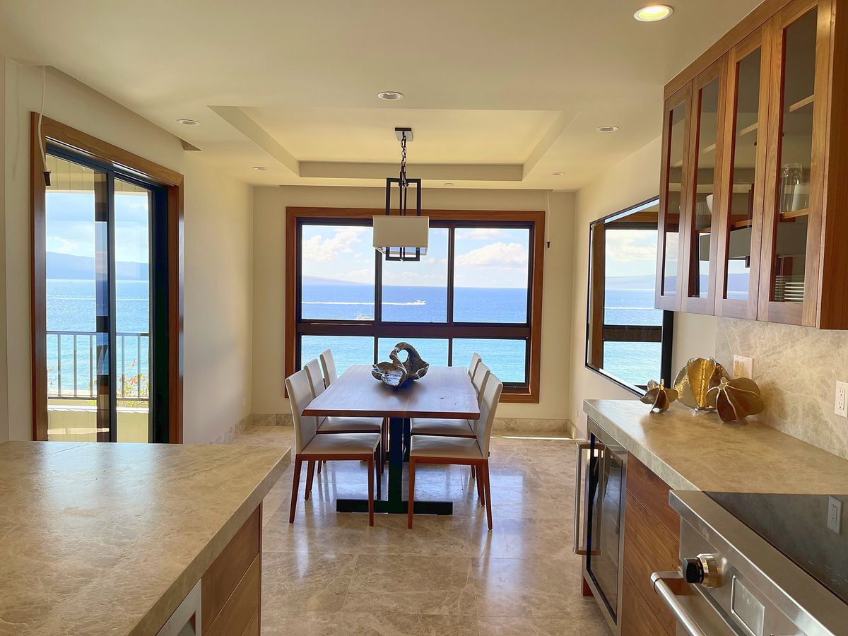 Renovated oceanfront condo kitchen and dining room with walnut cabinetry and stone floors